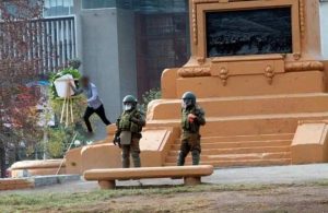 Manifestante se lleva ofrenda floral dejada por militares en retiro en monumento a Baquedano