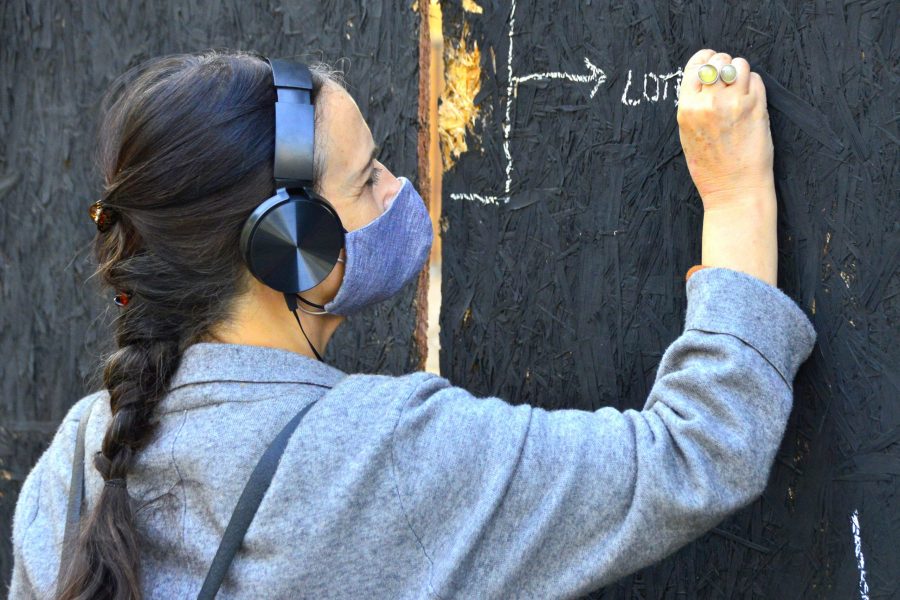 La antropóloga Francisca Márquez escribe sobre un panel de madera aglomerada como parte de una investigación.