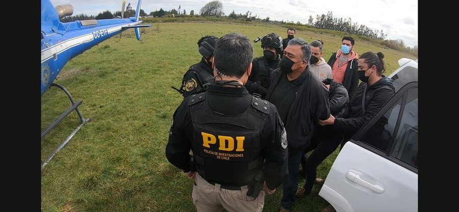 Personal de la PDI lleva a Héctor Llaitul esposado hasta un helicóptero para su traslado, luego de ser detenido en Cañete.
